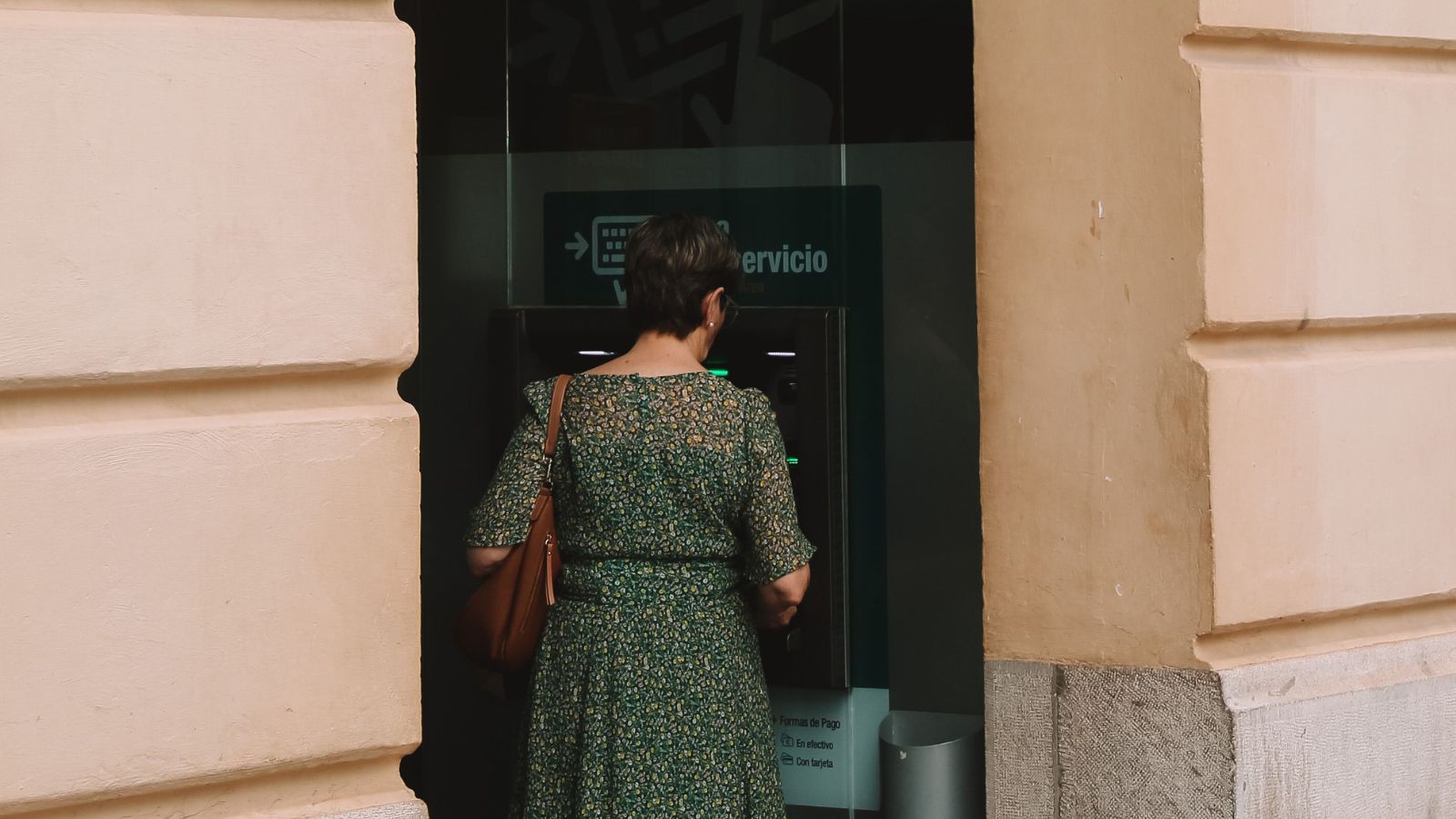 Woman Protected The Savings Her Grandma Set Aside For Her, But Her Mother Wanted Most Of It To Pay Her Own Bills Woman wearing a dress withdrawing money from an ATM