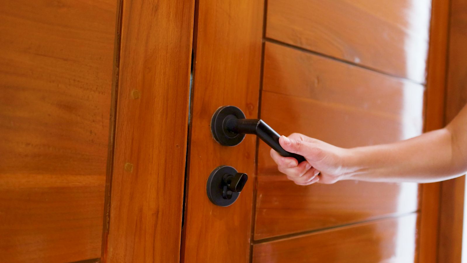 Woman Moved Into An Ex Council Flat, But Her Downstairs Neighbors Constant Noise Has Her Considering Moving Out Person holding the door knob to open the door