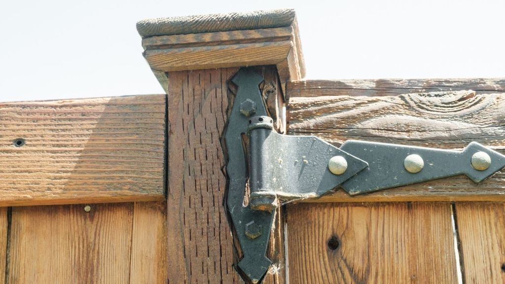 closeup of a metal hinge attached to a wooden fence