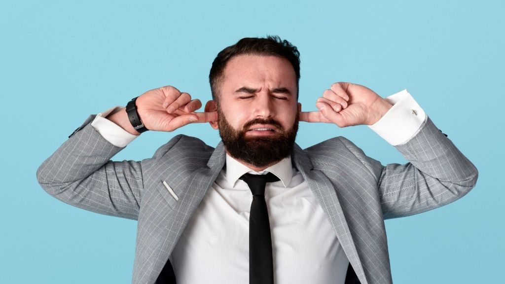 businessman trying to block out noise with his fingers in his ears
