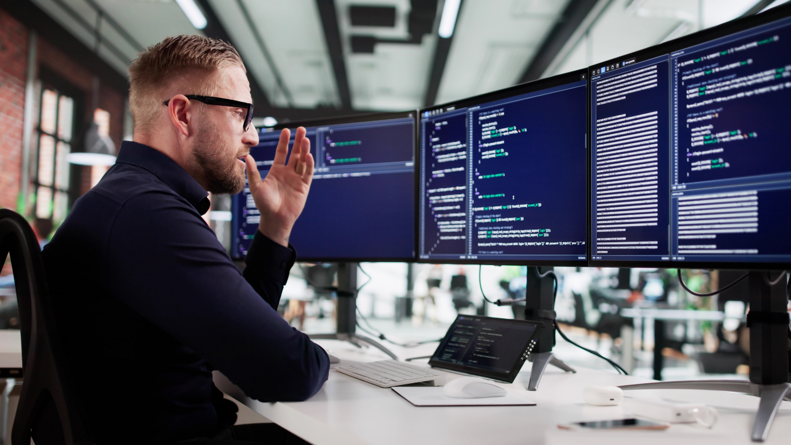 frustrated man looking at multiple computer monitors