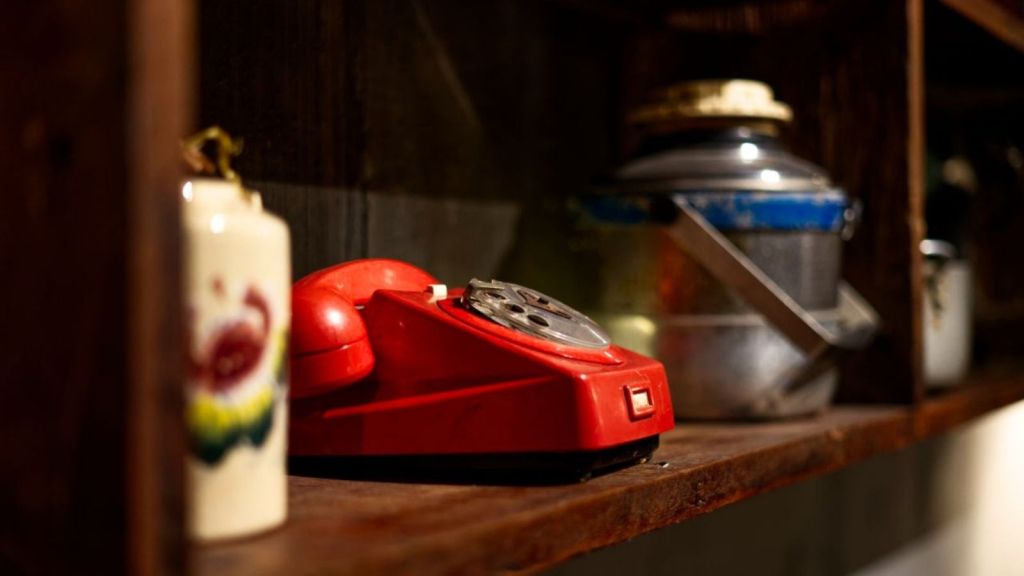 Red rotary phone on a shelf
