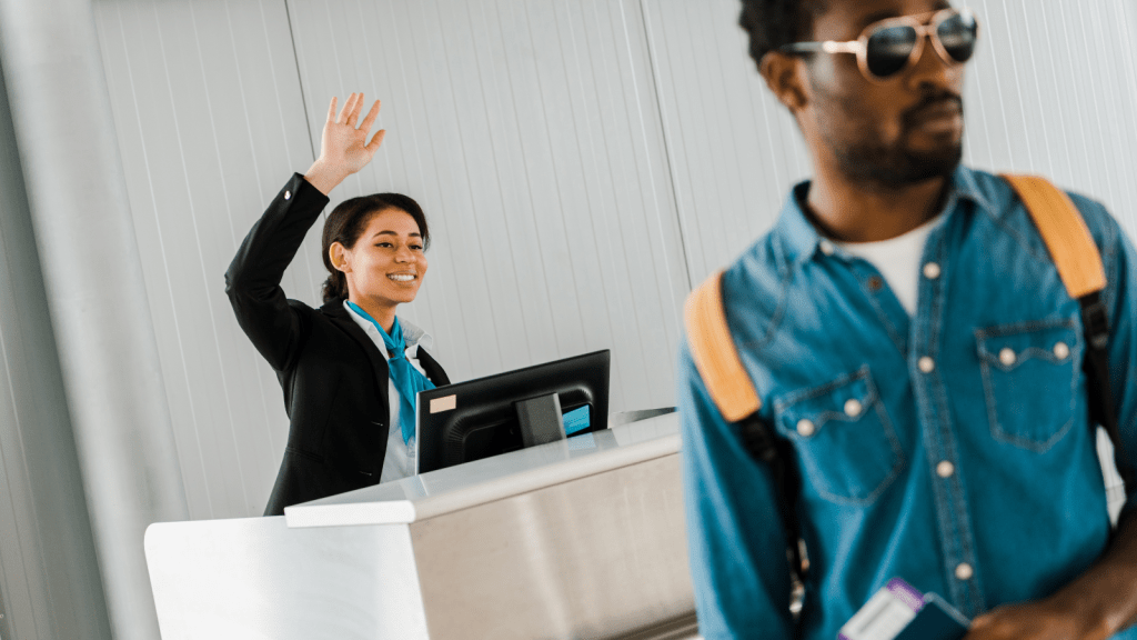 He Demanded an Upgrade to Business Class — The Employee Made Sure He Stayed in Economy Instead airline employee smiling at check in counter