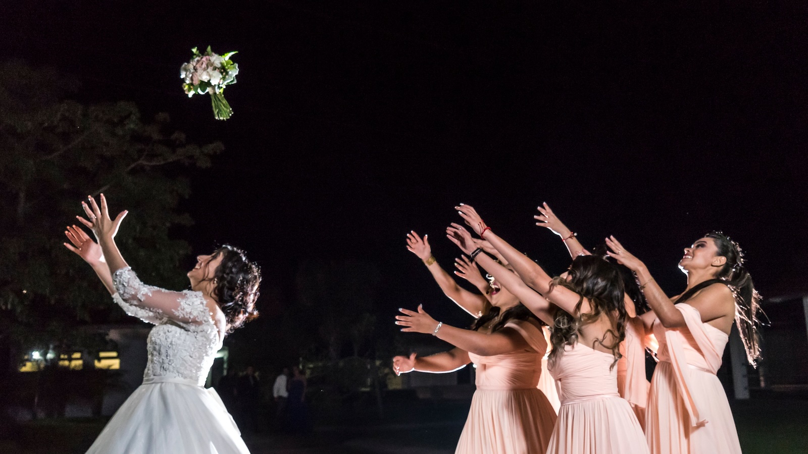bride throwing the bouquet to bridesmaids at wedding
