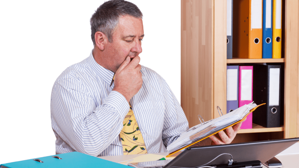 He Couldn’t Leave Before His Employer’s Required Notice Ended, So He Sat In The Office Doing Nothing While Operations Started Unraveling businessman browsing through a binder