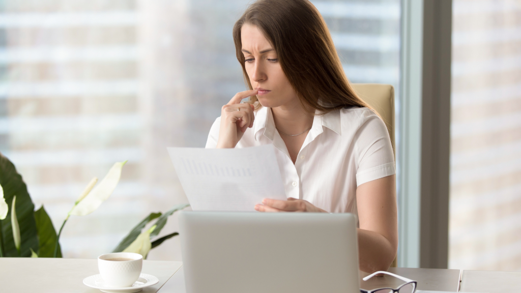 Employee Was Blocked From Pursuing A Side Hustle, So She Waited Until Her Boss Was On Vacation And Applied For A Demotion businesswoman looking at a piece of paper