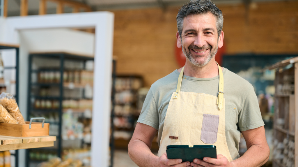 cheerful man grocery store holding tablet smiling