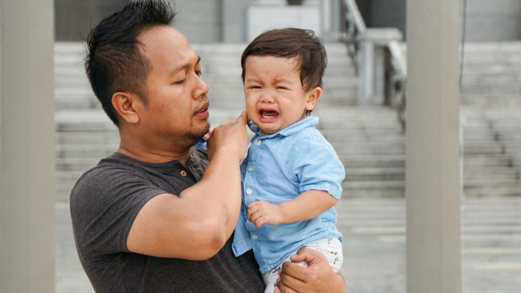 dad carrying a crying boy