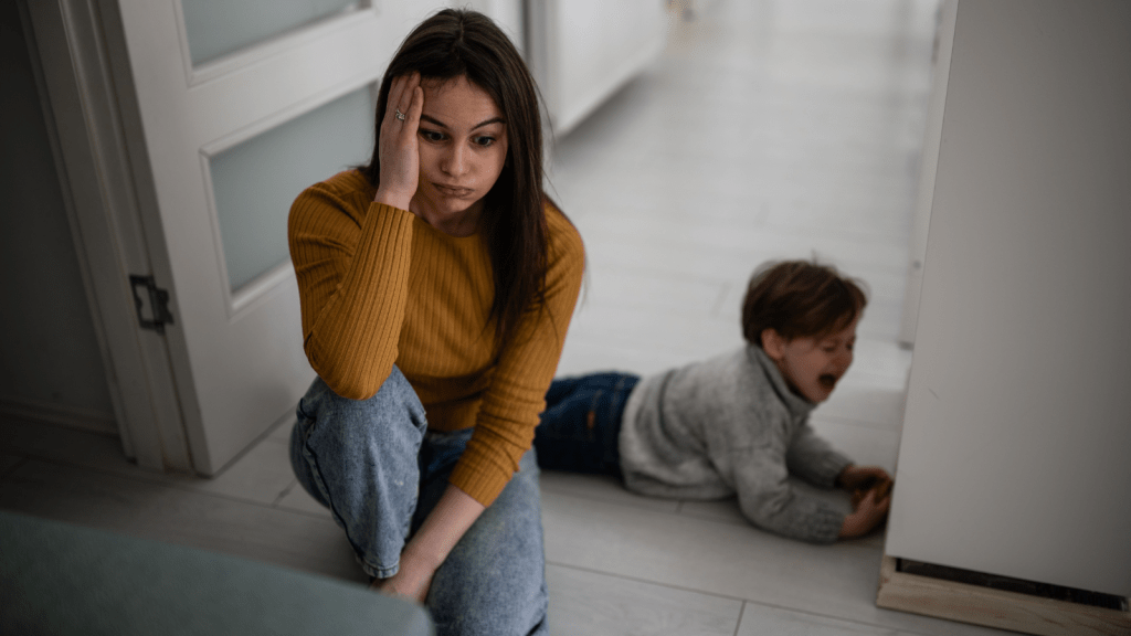 frustrated young mother kneeling with tantrum child boy