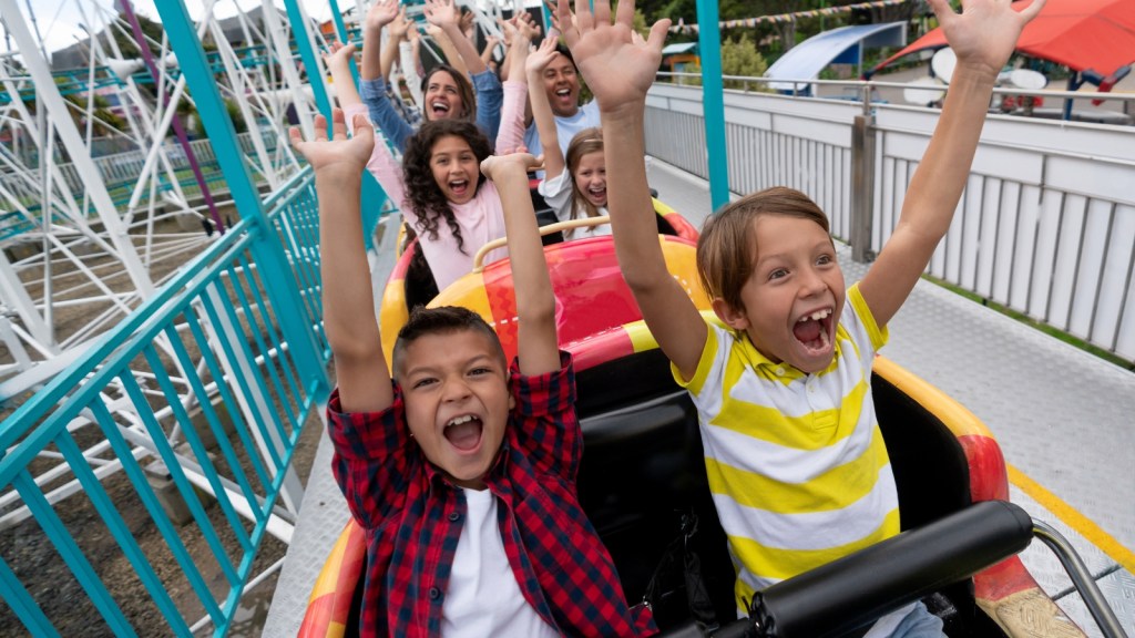 He Booked a Surprise Overseas Theme Park Trip for His Sons Birthday—Then His Wife Questioned Pulling the Kids Out of School for a Week happy kids on a rollercoaster