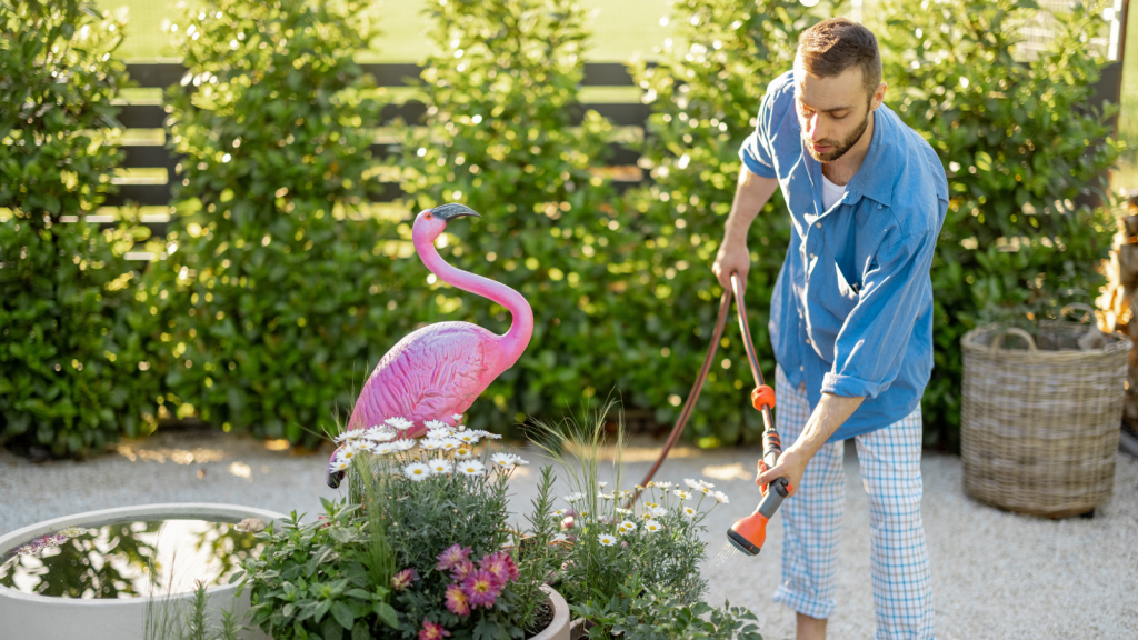 She Doesnt Live Under HOA Rules — So Her Neighbors Demand to Remove Her Flamingos Isnt Going Anywhere homeowner watering plants with pink lawn flamingo
