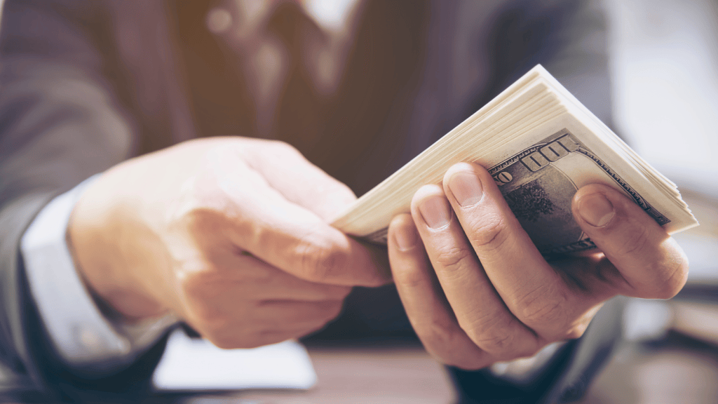 Man Exploited A Self Checkout Loophole, But His Repeated Transactions Quickly Drained The Stores Available Cash man holding a lot of cash
