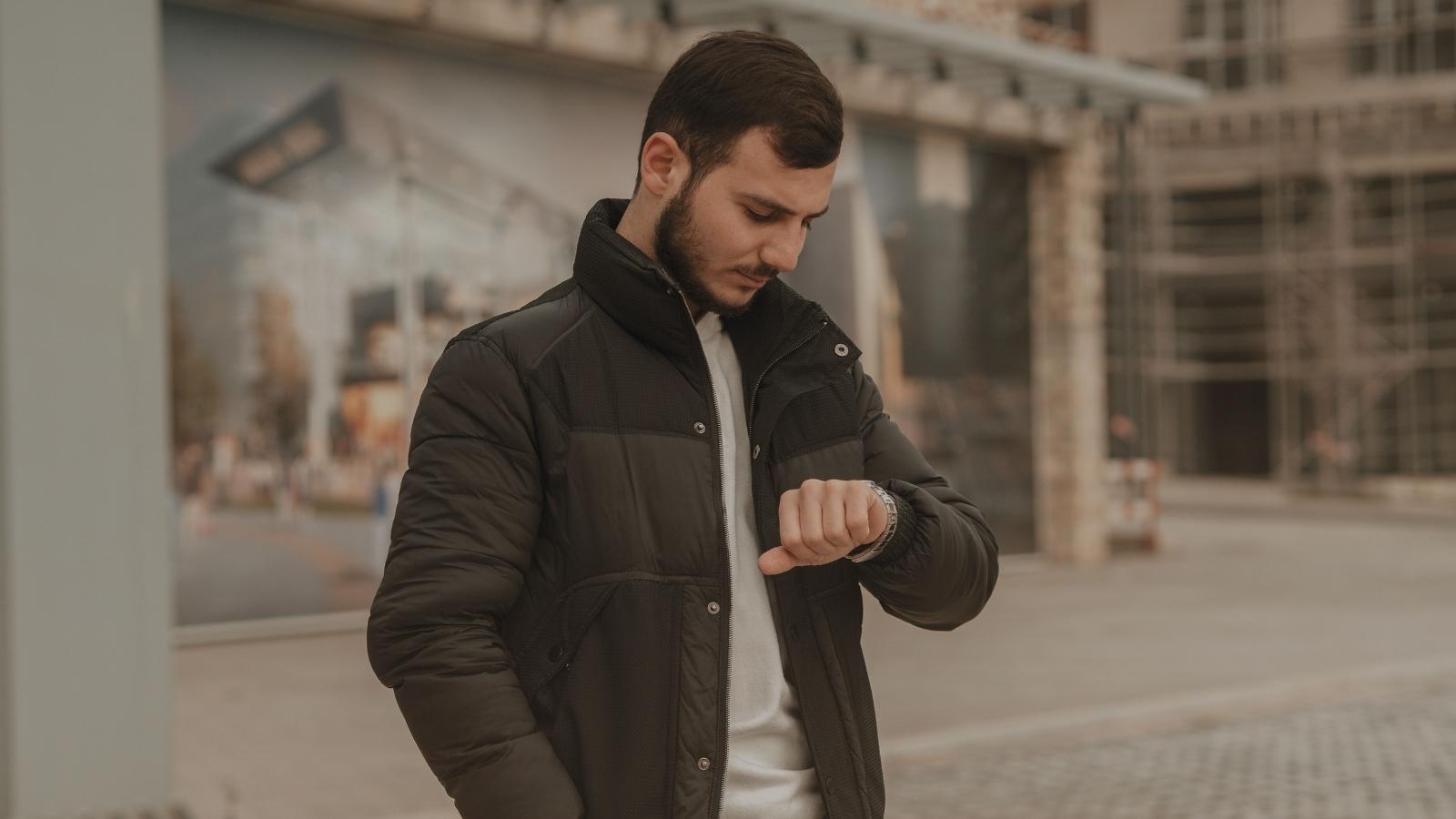 man in coat looking at his watch