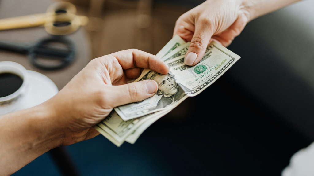 She Owed $2,400 for a Group Vacation She Promised to Repay—Then Demanded a $1,000 Emergency Loan for a Shopping Trip man lending cash to another person