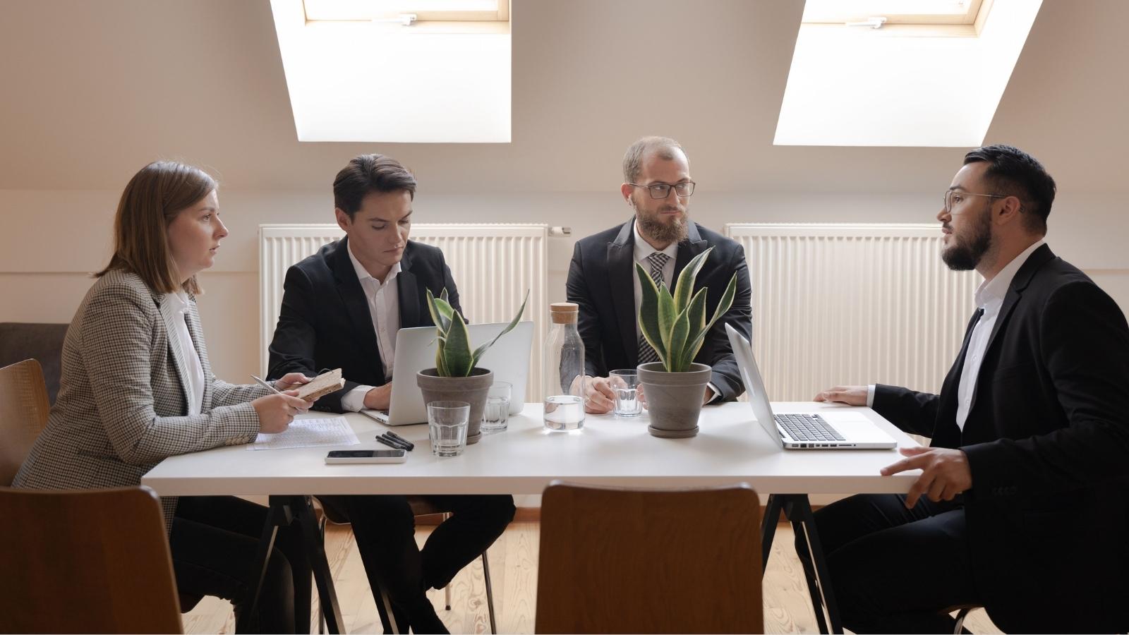 Employee Returned From A Cleared Suspension, But His Company Tried To Push Him Out With A Settlement Agreement people sitting in a meeting room