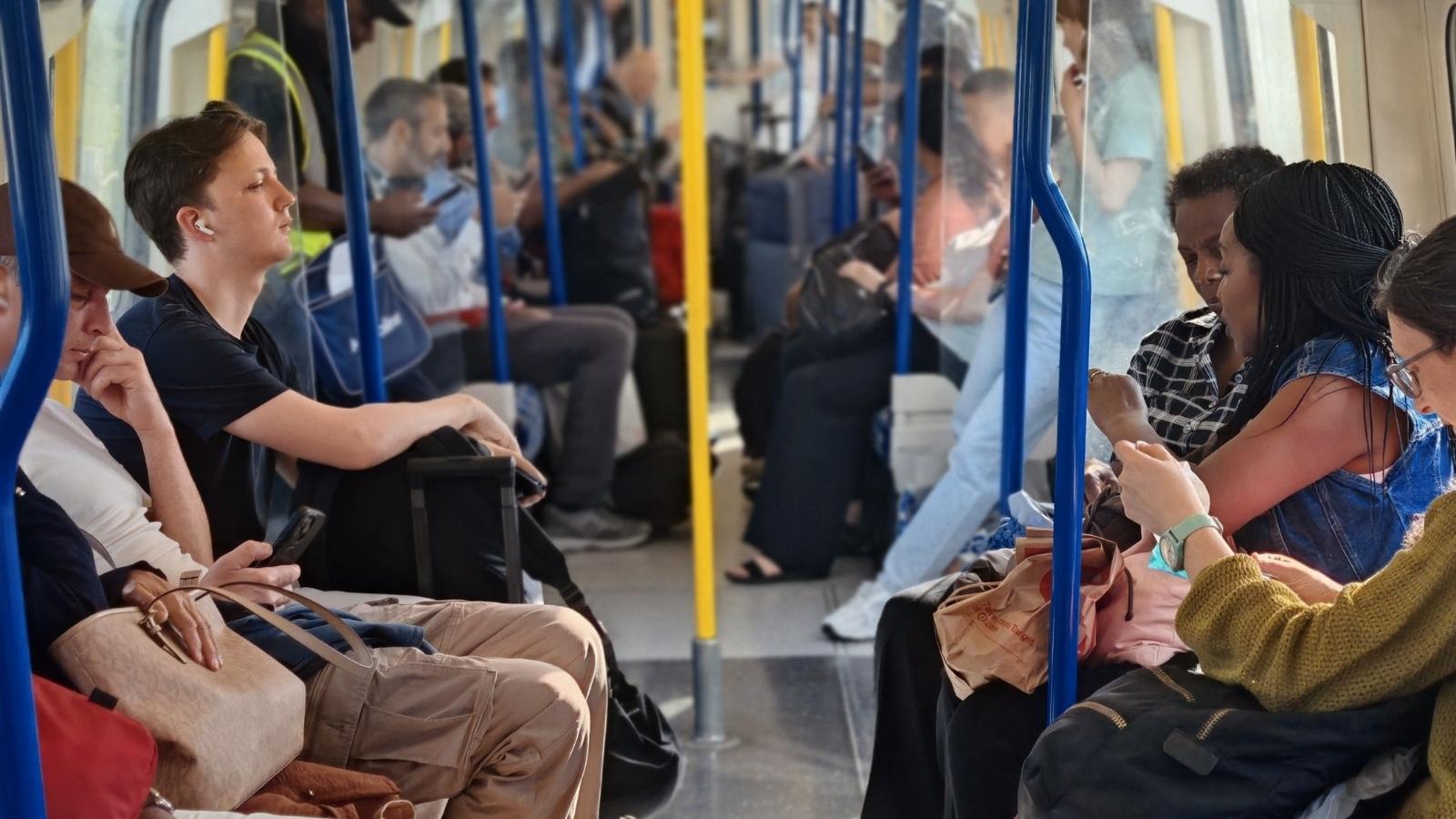 Tourists Claimed Their Empty Train Seat Was Reserved for a Friend—Then a Passenger Saw Them Use It for Luggage people sitting on a crowded train
