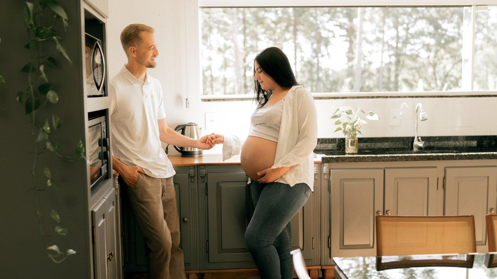 pregnant woman and husband standing in kitchen