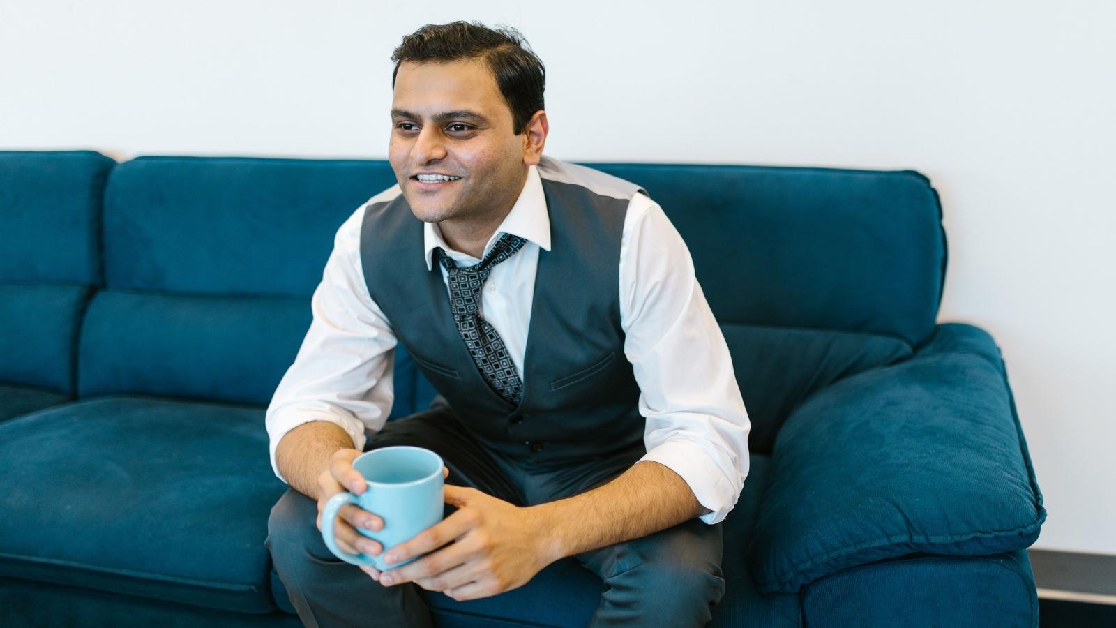 The Company Built a Wellness Room to Fight Burnout — Then Reprimanded an Employee for Using It Without Clocking Out professional man sitting on a blue couch
