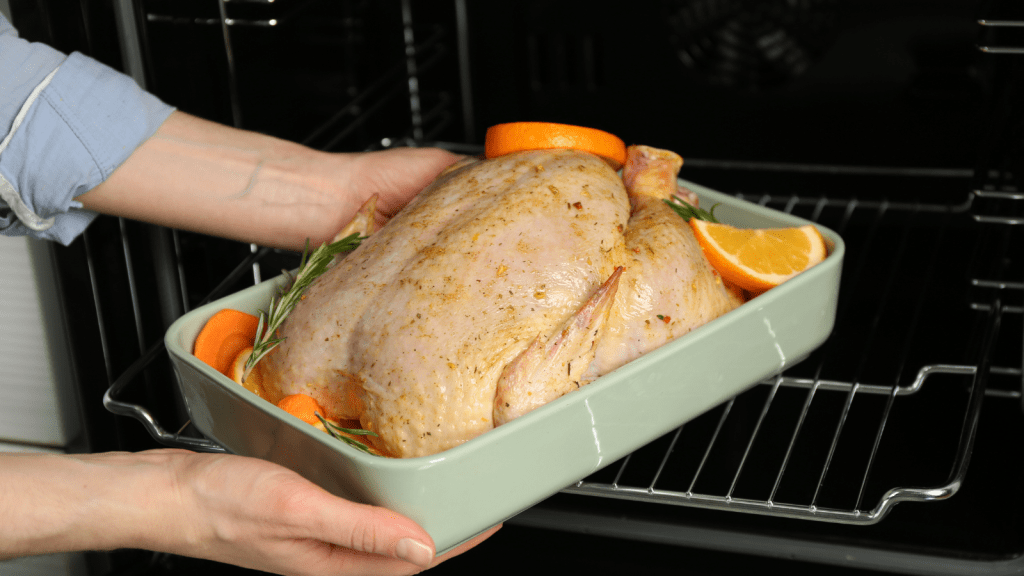 woman putting chicken in the oven