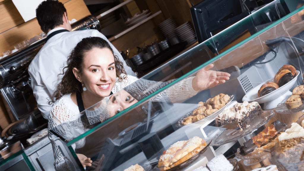 woman setting pastries and bakery items for sale in a coffee shop