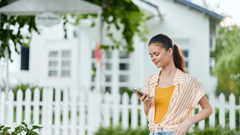 She Thought Her Inherited Home Was Ready For Her To Use, Yet Her Parents Had Already Turned It Into A Rental And Pocketed The Money young woman standing in front of her house smiling at phone