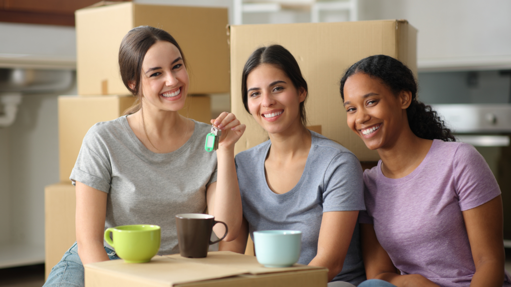 young women moving in to flat together holding keys