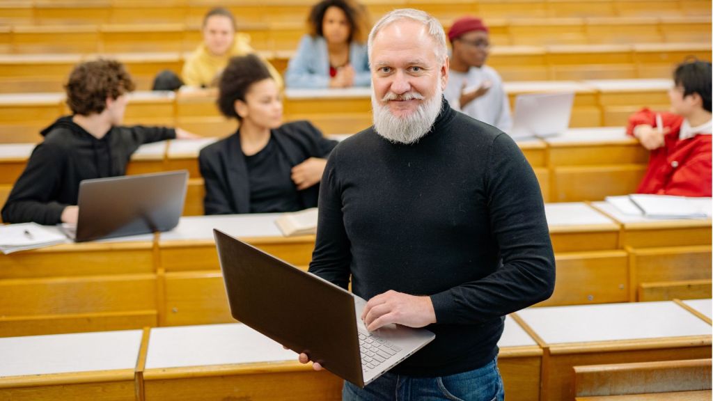Man in classroom holding a laptop