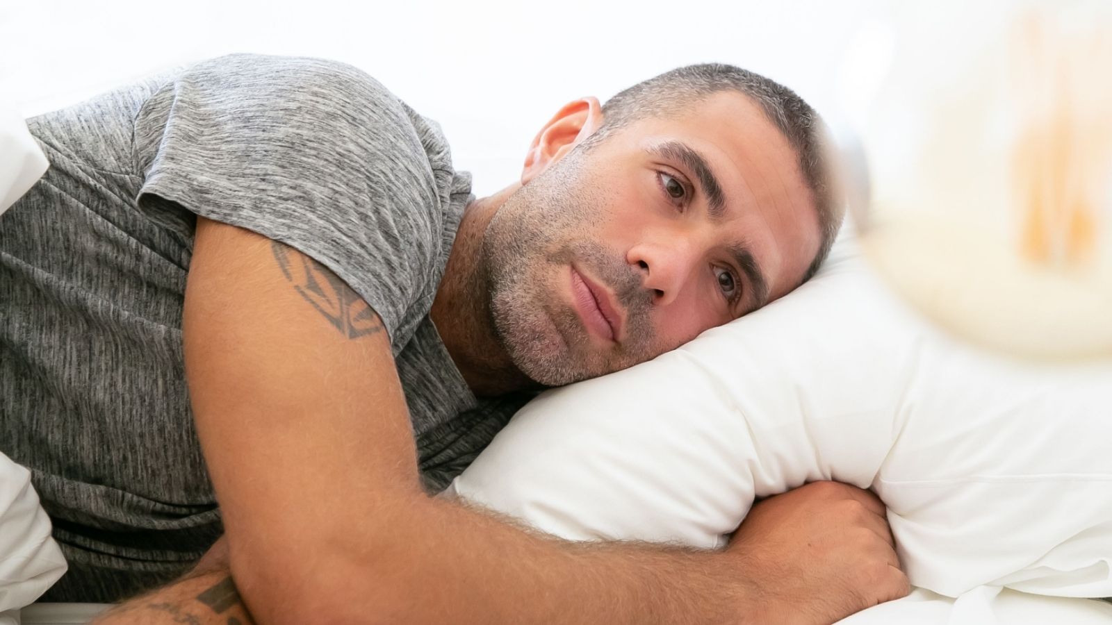 Man lying in bed, looking pensive