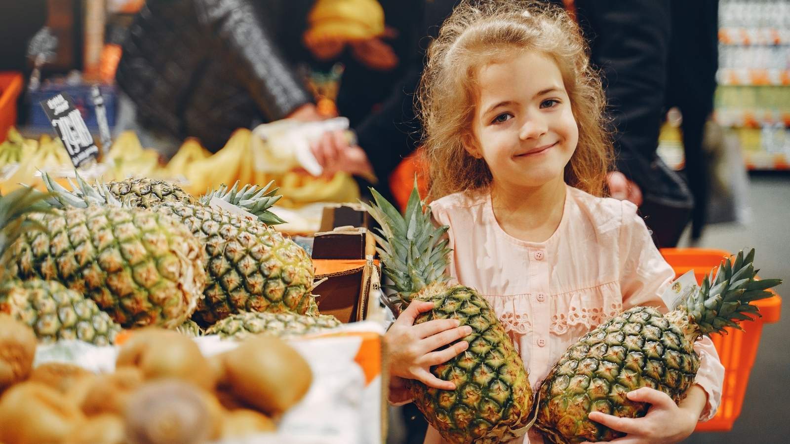 Mother Calls Customer An “Old Hag” After She Shoves A Shopping Cart Into Her Daughter And Refuses To Apologize Child in the grocery store holding pineapples