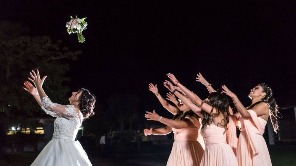 Bride throwing her bouquet to a group of women