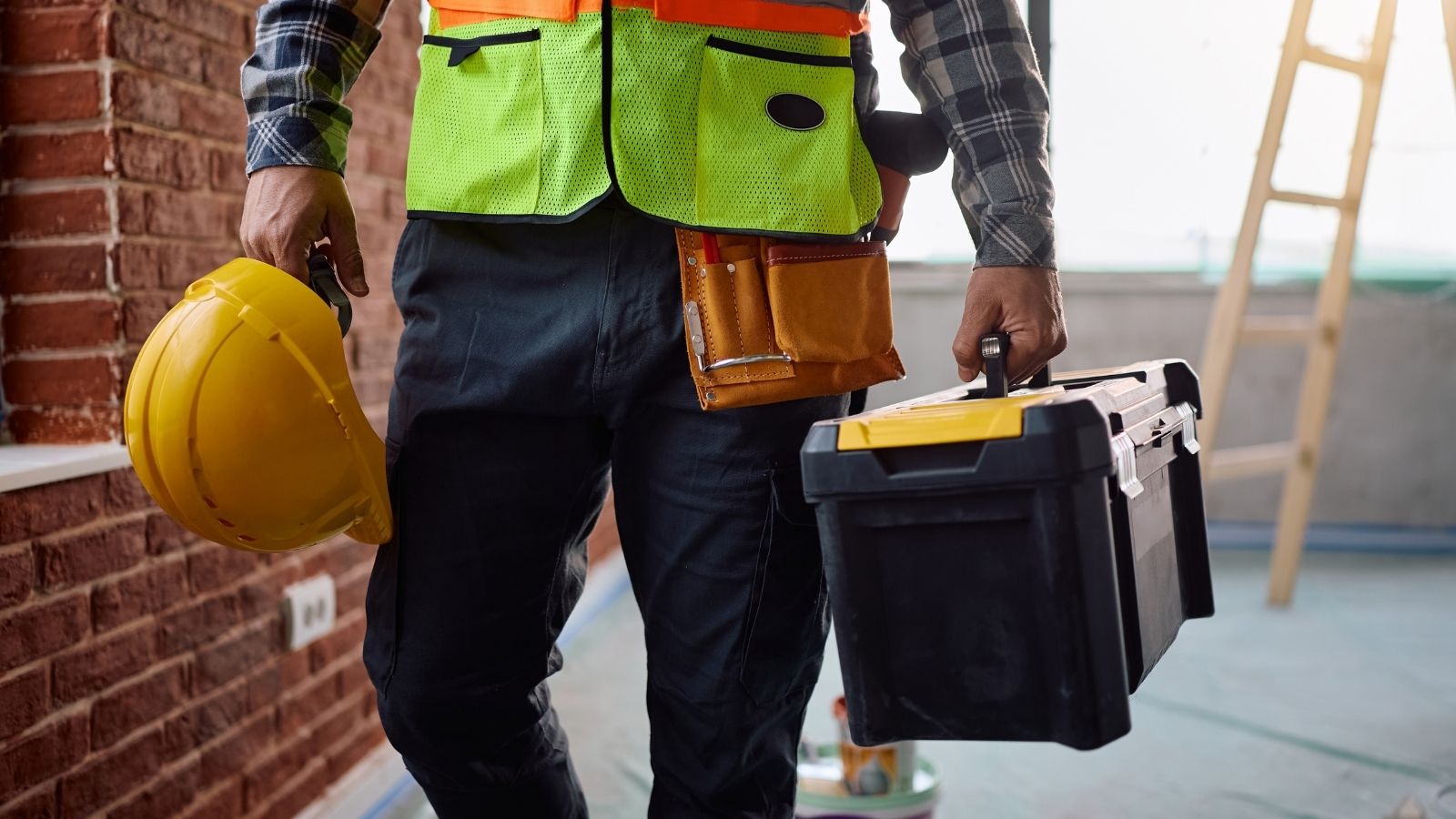 construction worker carrying a hardhat and a toolbox