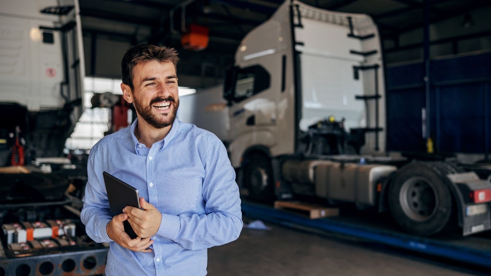 He Thought The Trucking Companys Price Was Too High, So The Manager Took Him Up On His Flat Rate Idea smiling man holding a tablet standing in front of semi trucks