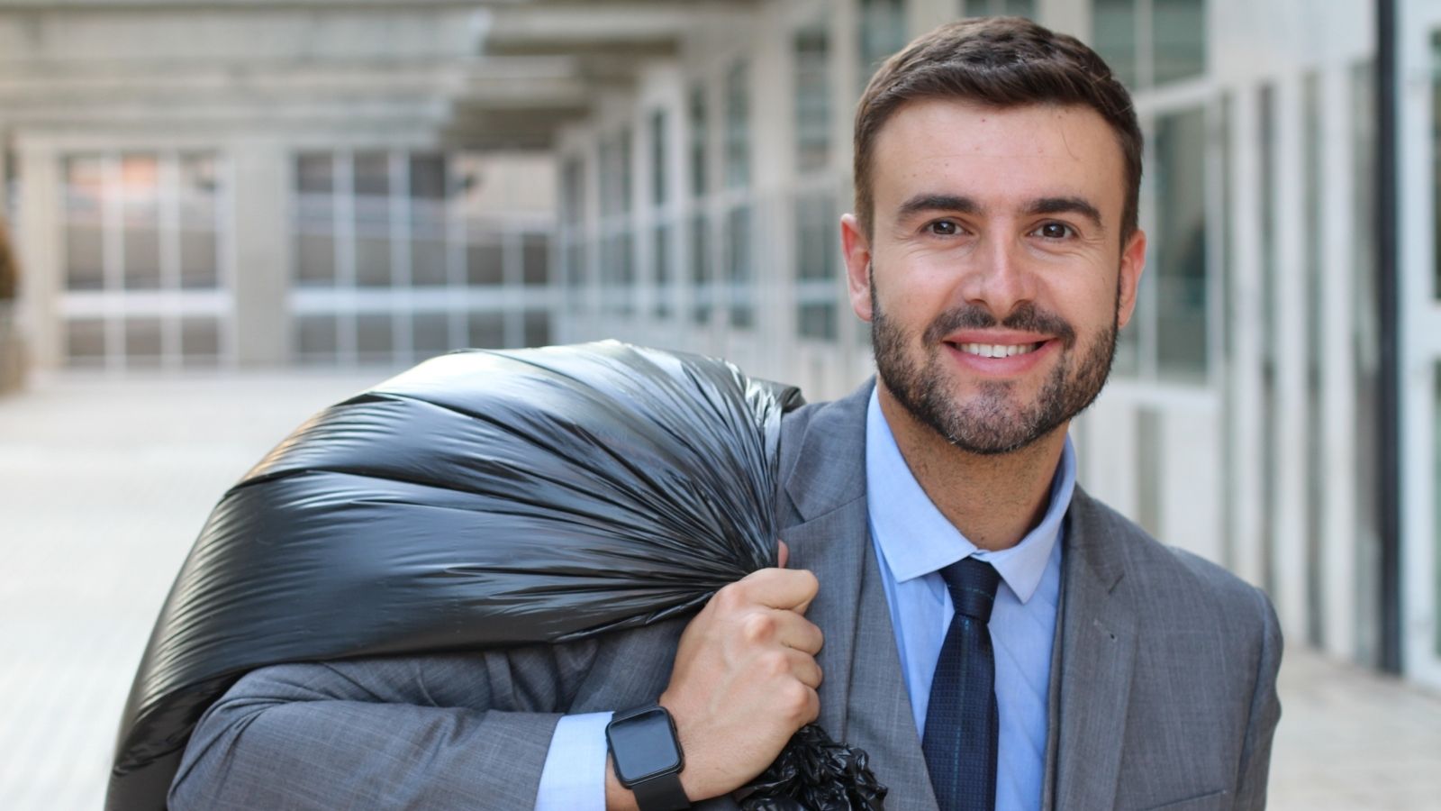 He Was Scolded for a 45 Minute Lunch—Until He Enforced a Rigid Handover Protocol That Trapped His Accuser at the Desk smiling businessman holding a trash bag
