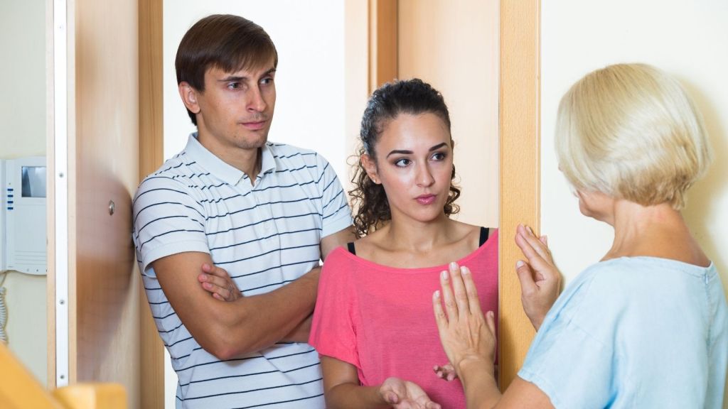 upset older woman arguing with neighbors in doorway