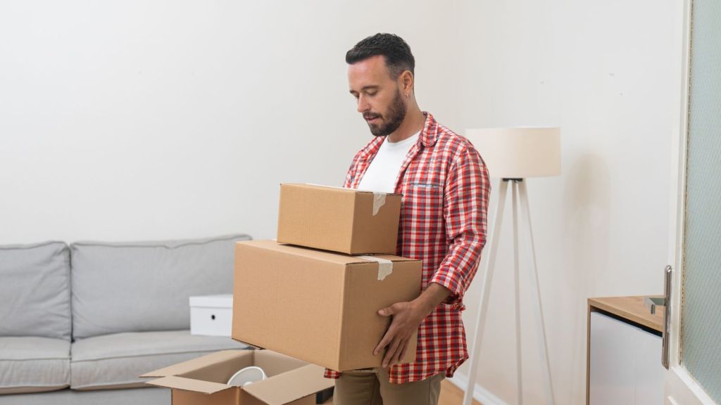 man looking down while holding moving boxes