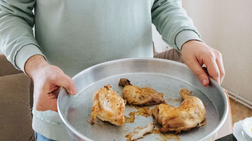 Man holding a tray of cooked chicken parts