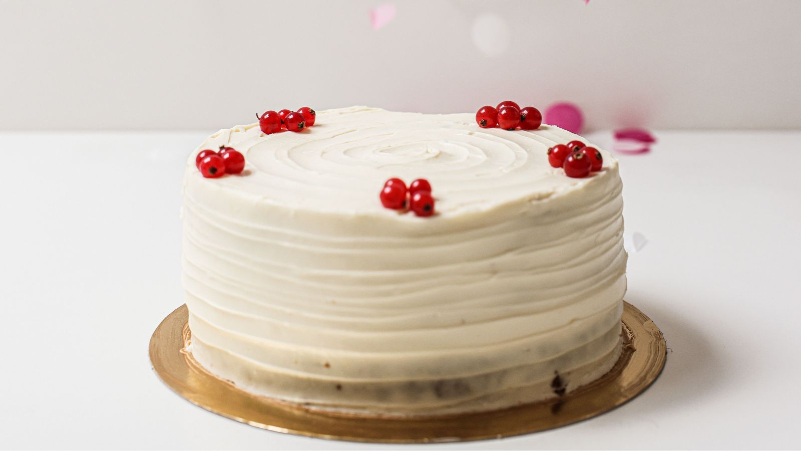 She Ordered a Custom Minimalist Cake—Until Her Sister Showed Up With a Neon Disaster A plain white cake with small red toppers