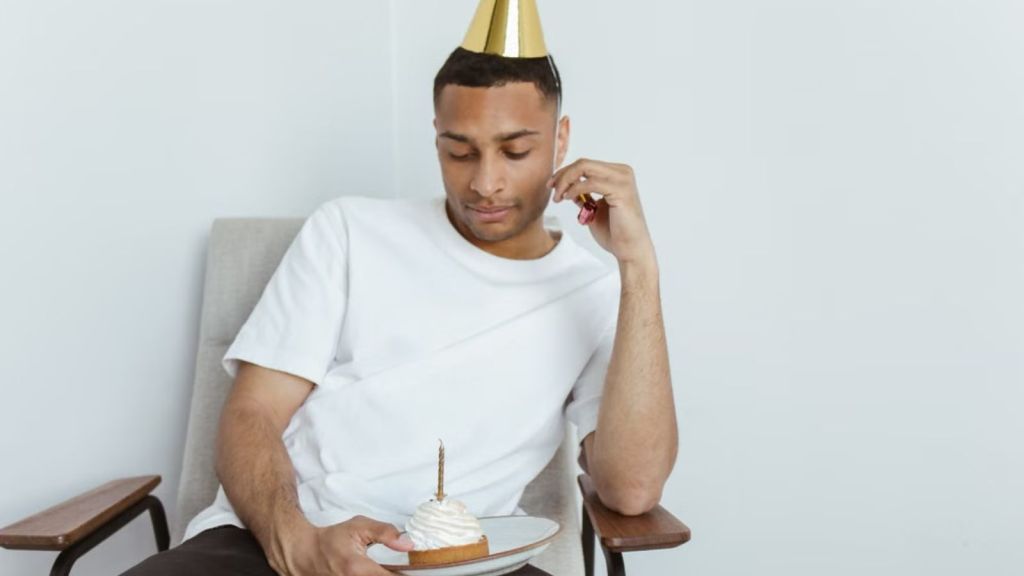 Man feeling sad as he celebrates his birthday alone with a cake