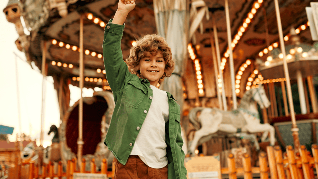 boy stands in front of carousel