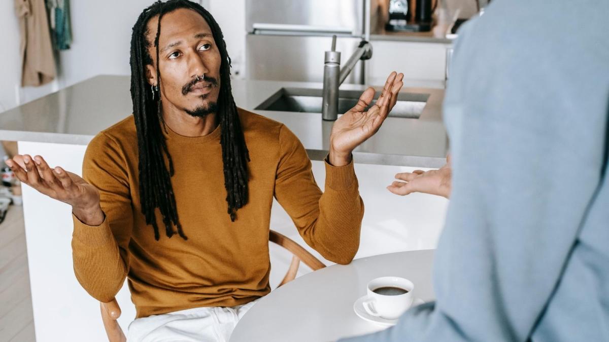 He Gave His Friend Free Utilities, Streaming, and a Private Room—Only for the Friend to Stash Away Savings Instead of Paying Rent man shrugging at the kitchen table