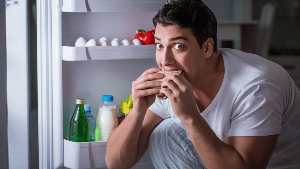 man sneaking food out of fridge at night