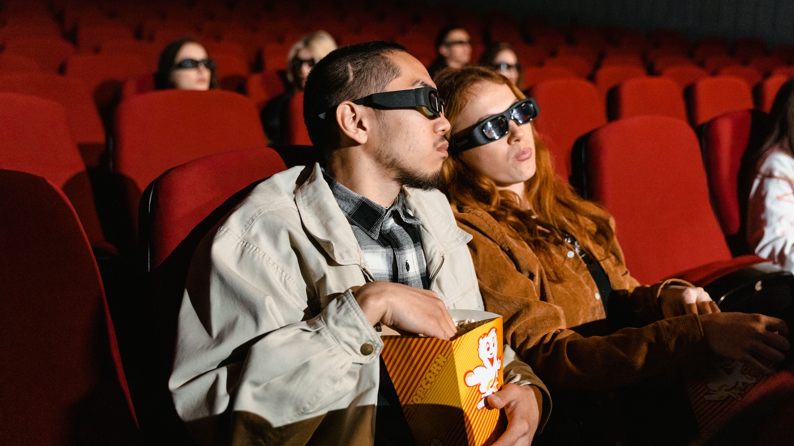 man and woman seeing a 3D movie in the theater, eating popcorn
