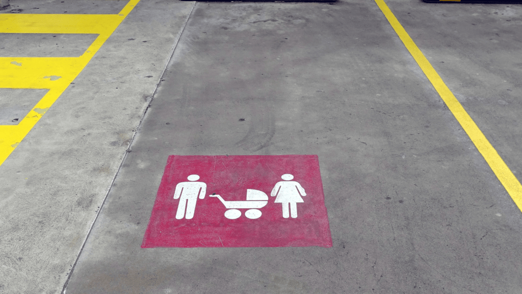 Mom Still Uses Parent And Child Parking Spaces With Her 18 Year Old Son, But He Thinks Its Time To Stop parking spot painted with symbols of child, dad, mom and baby stroller